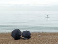 Paddle boarder on the sea with two umbrellas in foreground