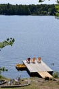 Paddle boat and row of red and yellow Muskoka chairs casting shadows on dock at Spring Lake Royalty Free Stock Photo