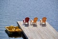 Paddle boat and row of red and yellow Muskoka chairs casting shadows on dock at Spring Lake Royalty Free Stock Photo