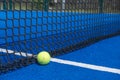 A paddle tennis ball is sitting on a blue court with a net, racket sport Royalty Free Stock Photo