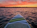 Paddleboard floating on the water with the colorful light of sunset reflecting off the waves at dusk Royalty Free Stock Photo