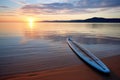 a paddleboard resting on a sandy beach at sunrise Royalty Free Stock Photo