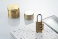 Padlock on a calculator with coins in the background