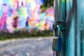 padlock closes a green iron gate with multicolored art concept in blurred graffiti Royalty Free Stock Photo