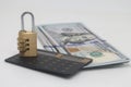Padlock on a hundred dollar bill and a calculator on a white background, saving capital and savings.