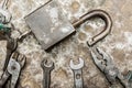 Padlock and old worn tool on rumpled shabby metal, close-up abstract background
