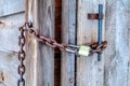 Padlock and rusty metal chain on the wooden door and handle of outdoor bathroom Royalty Free Stock Photo