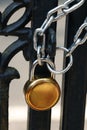 Padlock and strong steel chain wrapped around the metal entrance gate