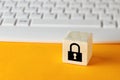 Padlock symbol on wooden cube against computer keyboard background. Data protection or cyber security concept