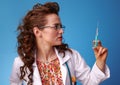 Paediatrician woman looking at syringe on blue