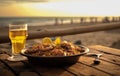 Paella and beer on a wooden table on a beach Royalty Free Stock Photo