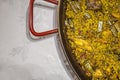 Paella chicken and rabbit dish in its pot served on the table with white tablecloth