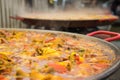 The cooking process of paella in a huge frying pan.