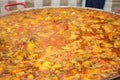 The cooking process of paella in a huge frying pan.