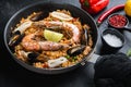 Paella traditional spanish dish served in frying pan, on black textured surface Royalty Free Stock Photo