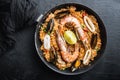 Paella traditional spanish dish served in frying pan, on black textured surface, top view Royalty Free Stock Photo