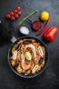 Paella traditional spanish dish served in frying pan, on black textured surface, top view Royalty Free Stock Photo