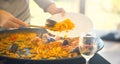 Paella. Traditional spanish food. Person putts seafood paella from the fry pan to plate. Paella with with mussels and squids