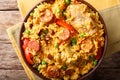 Paella Valenciana with meat, sausage chorizo, vegetables and spices close-up in a bowl. Horizontal top view