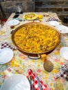 Paellera with a freshly cooked authentic Valencian paella, to serve on a table with the dishes set, salad, glasses and the floral Royalty Free Stock Photo