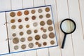 Page of numismatics album with different coins on a white wooden table