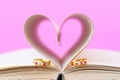 Pages of book curved heart shape and weeding ring Royalty Free Stock Photo