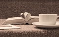 Pages of open book rolled in heart shape with coffee on table Royalty Free Stock Photo