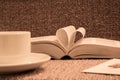 Pages of open book rolled in heart shape with coffee on table Royalty Free Stock Photo