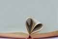 Pages of open book rolled in heart shape with light gray background Royalty Free Stock Photo