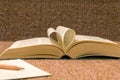 Pages of open book rolled in heart shape on table Royalty Free Stock Photo
