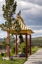 Pagoda with a bell in a Buddhist monastery on top of a mountain against a blue sky and green grass