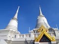 two white bell shape pagoda with golden gable carving a Thai pattern and bright blue sky background at wat Asokaram