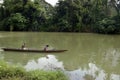 Man ushering a woman passenger on small tiny boat on murky river using paddle