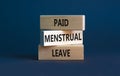 Paid menstrual leave symbol. Concept words Paid menstrual leave on wooden blocks. Beautiful grey table grey background. Business