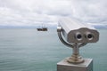 Paid observation point for the sea through binoculars, against a blurred background of the sea and a distant ship and sailboat Royalty Free Stock Photo