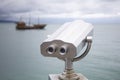 Paid observation point for the sea through binoculars, against a blurred background of the sea and a distant ship and sailboat Royalty Free Stock Photo