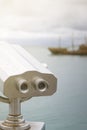 Paid observation point for the sea through binoculars, against a blurred background of the sea and a distant ship and sailboat Royalty Free Stock Photo