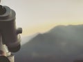 Paid outdoor tourist telescope against the backdrop of extending mountains and a river