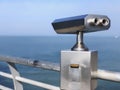 Paid outdoor tourist telescope made of stainless steel on the sea coast over blue sky background