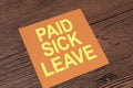 Paid Sick Leave, text words typography written on paper against wooden background, life and business motivational inspirational