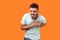 Pain in chest. Portrait of sick stressed out brunette man suffering sudden heart attack. isolated on orange background Royalty Free Stock Photo