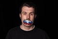 Pain. Conceptual portrait of young man with three colors duct tape over his mouth isolated on dark background Royalty Free Stock Photo