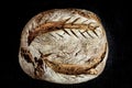 Loaf or miche of French sourdough, called as well as Pain de campagne, on display isolated on a black background.