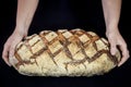Loaf or miche of French sourdough, called as well as Pain de campagne, on display isolated on a black background held by female