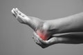 Pain in the foot. Massage of female feet. Pain in the human body on a gray background Royalty Free Stock Photo