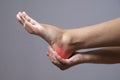 Pain in the foot. Massage of female feet. Pain in the human body on a gray background