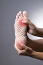 Pain in the foot. Massage of female feet. Pain in the human body on a gray background Royalty Free Stock Photo