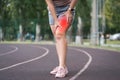 Pain in the hip during training, muscles cramped, massage of female leg on a sports ground after workout Royalty Free Stock Photo