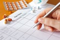 Pain management concept: weekly pain diary spreadsheet with pen and medicine. Royalty Free Stock Photo