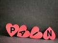 Pain text on red heart shaped background. Stock photo.